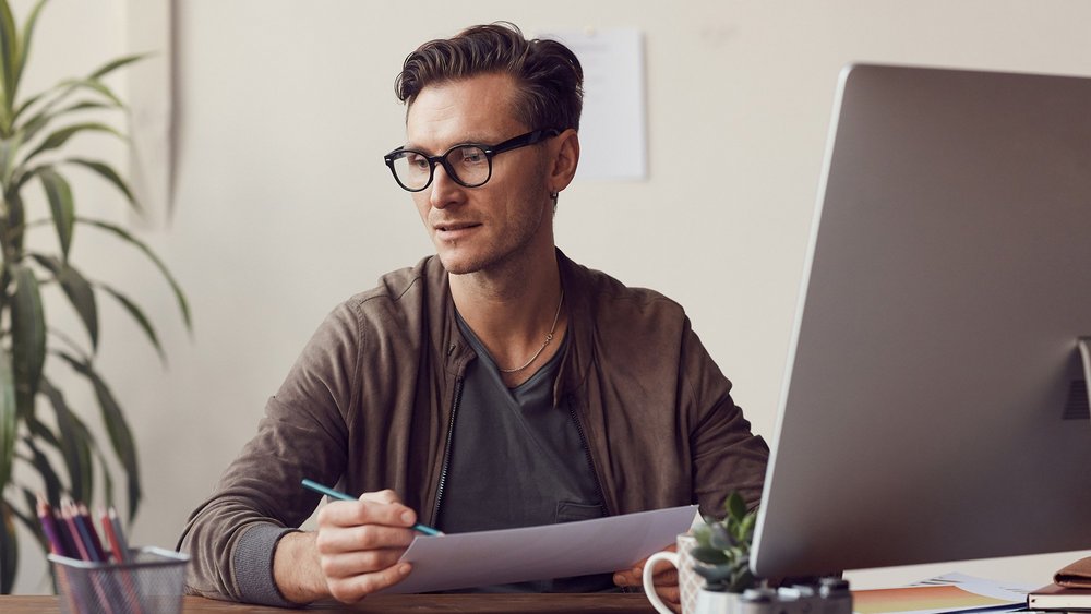 a decorative element: a young man wearing glasses sitting at a desk and working