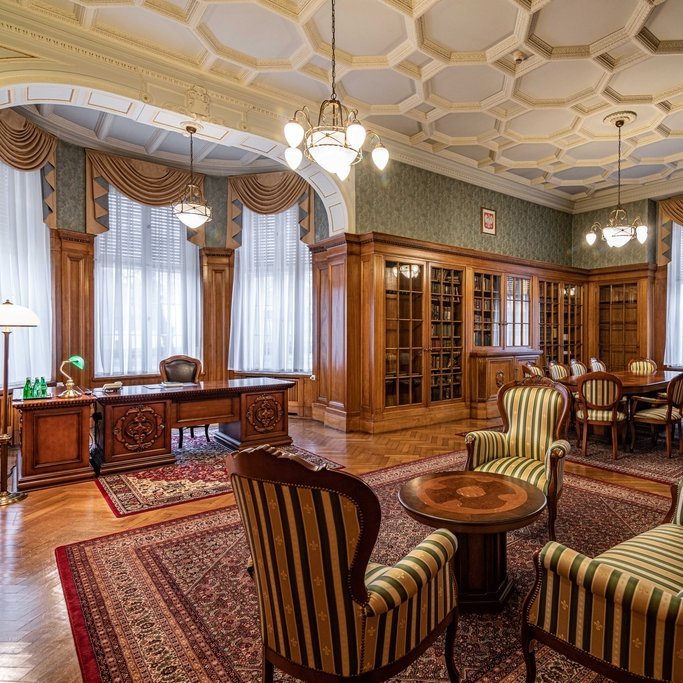 wnętrze gabinetu m.in biurko, szafy biblioteczne i stolik z krzesłami