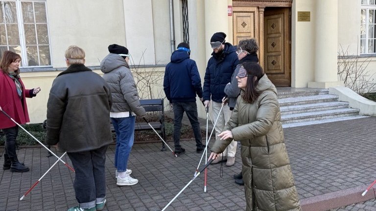 a group of blindfolded people moving around using a white cane